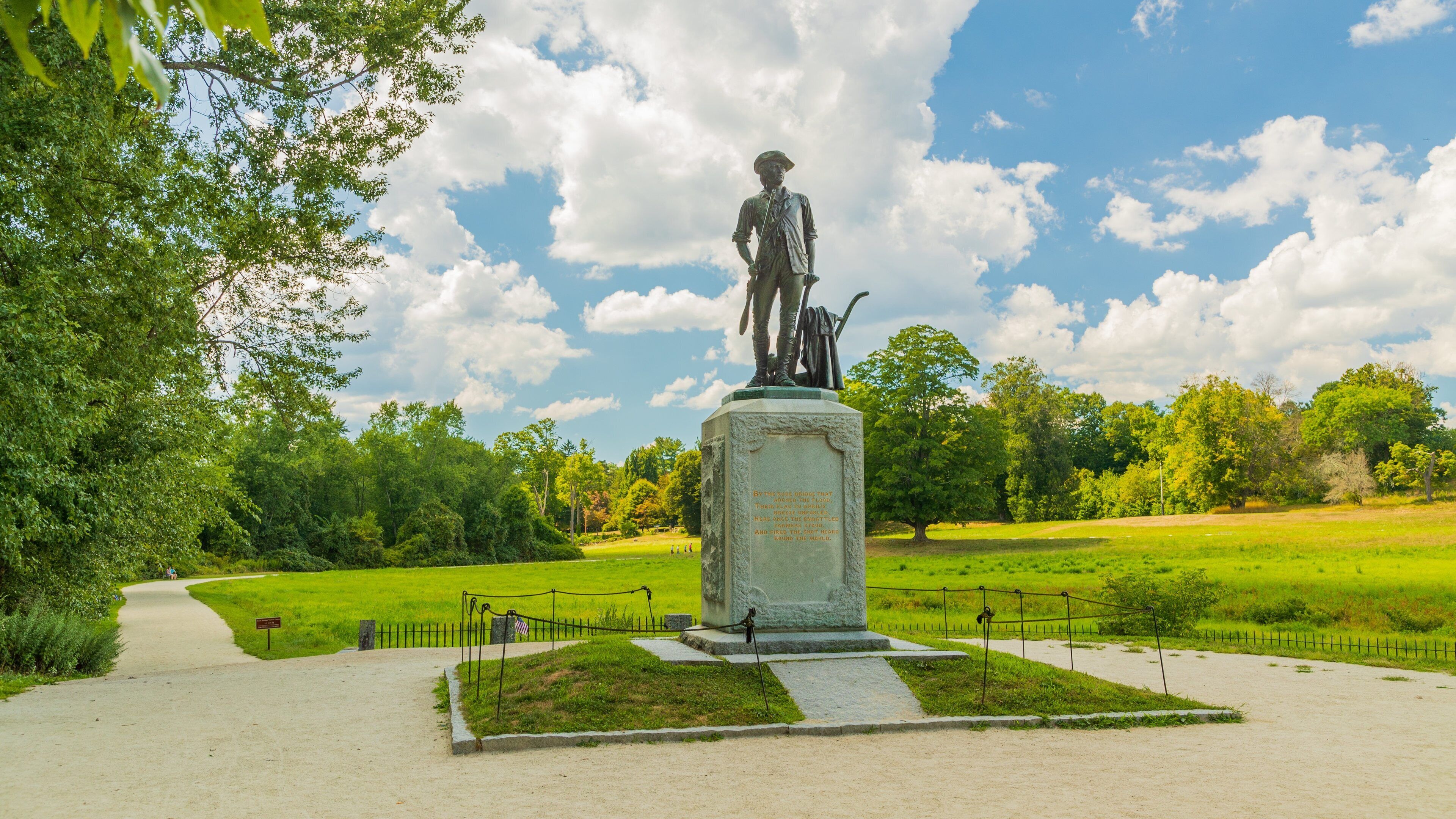 Una estatua en un parque con cielo despejado y árboles verdes.