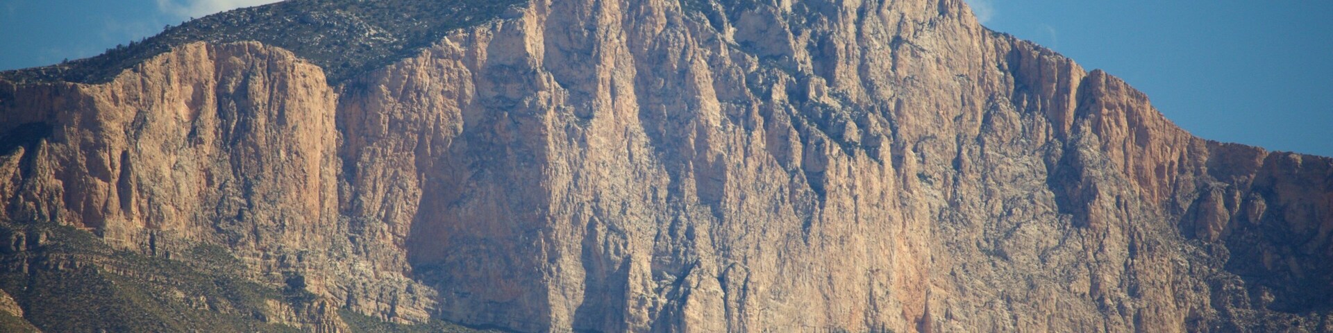 A rugged mountain with steep cliffs and sparse vegetation.