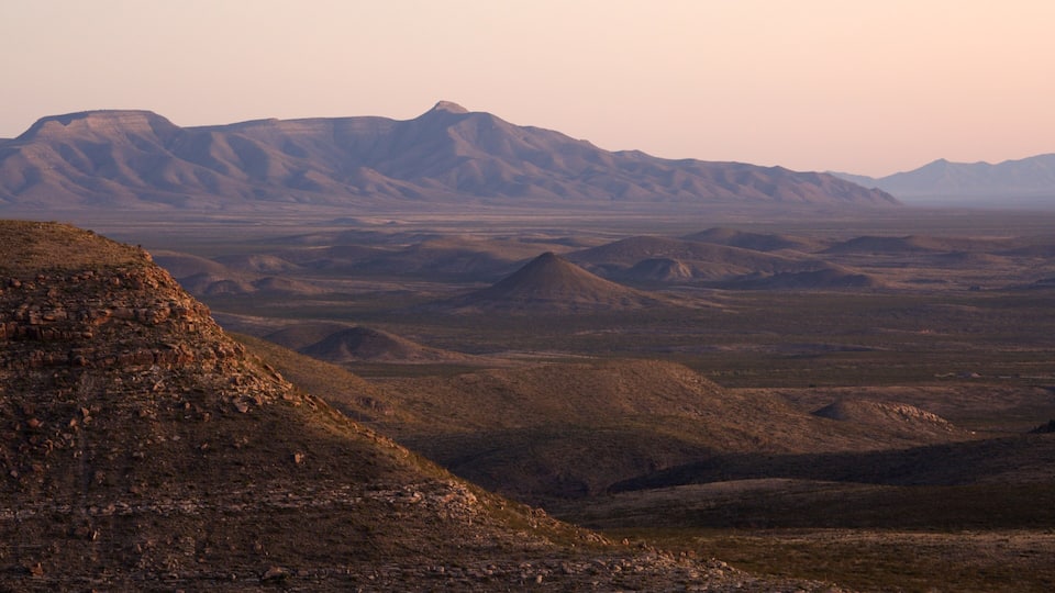 A vast desert landscape with rolling hills and distant mountains.