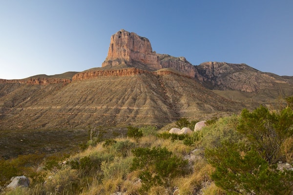 Ein zerklüfteter Berg mit einem markanten Gipfel und einer tafelartigen Mesa im Vordergrund.
