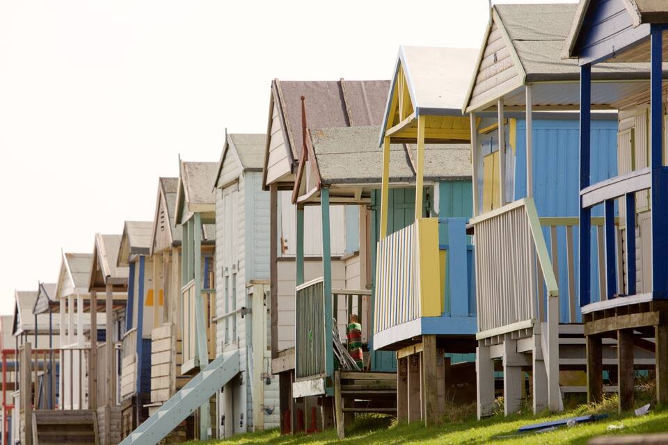A row of colorful wooden beach huts with sloped roofs.