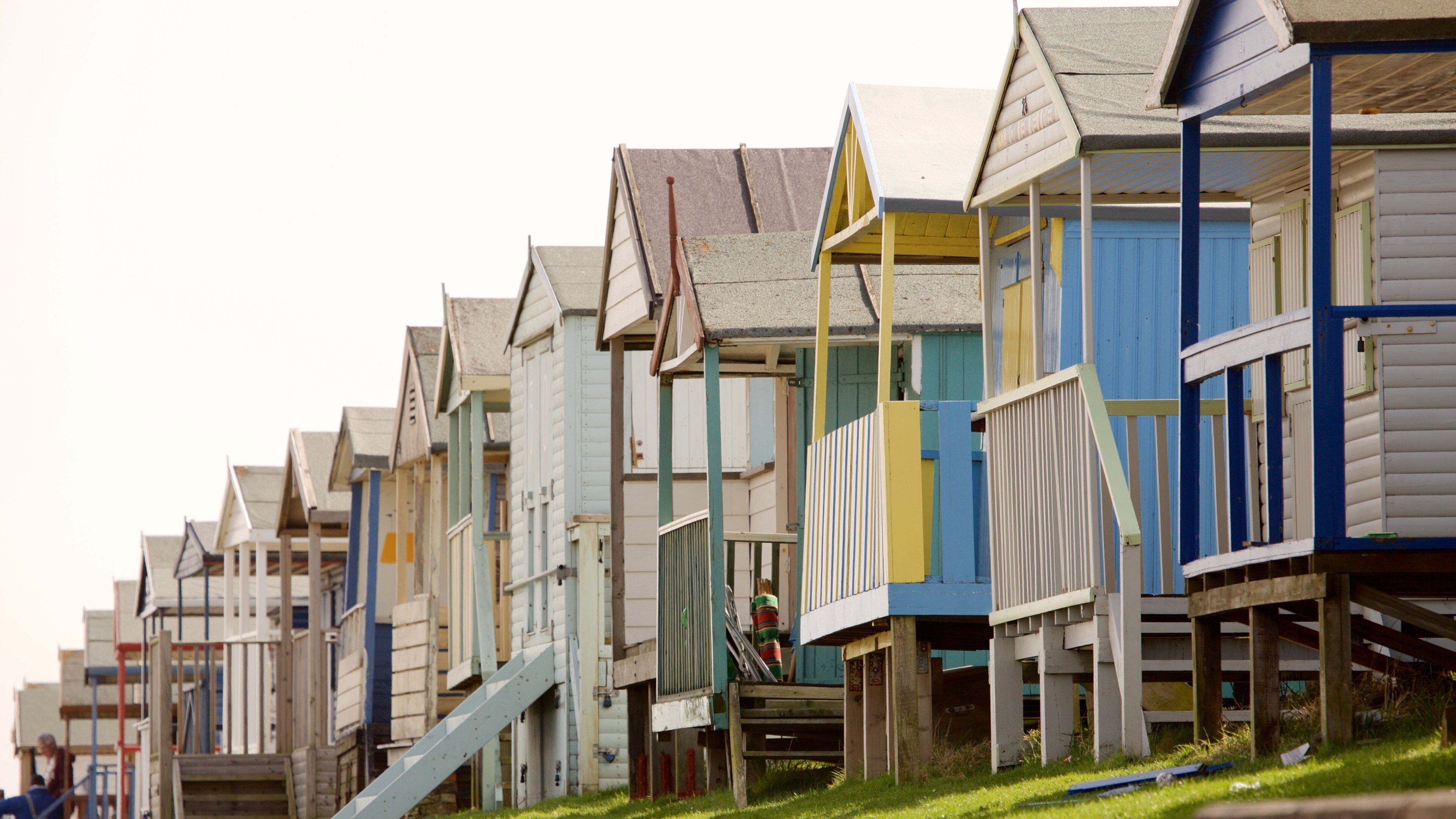 A row of colorful wooden beach huts with sloped roofs.