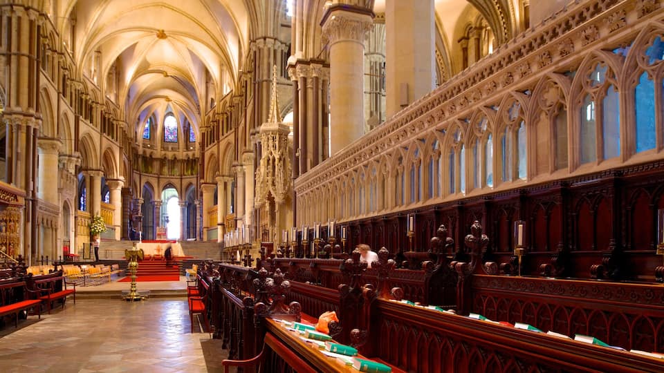 A grand cathedral interior with high vaulted ceilings, ornate wooden pews, and stained glass windows.