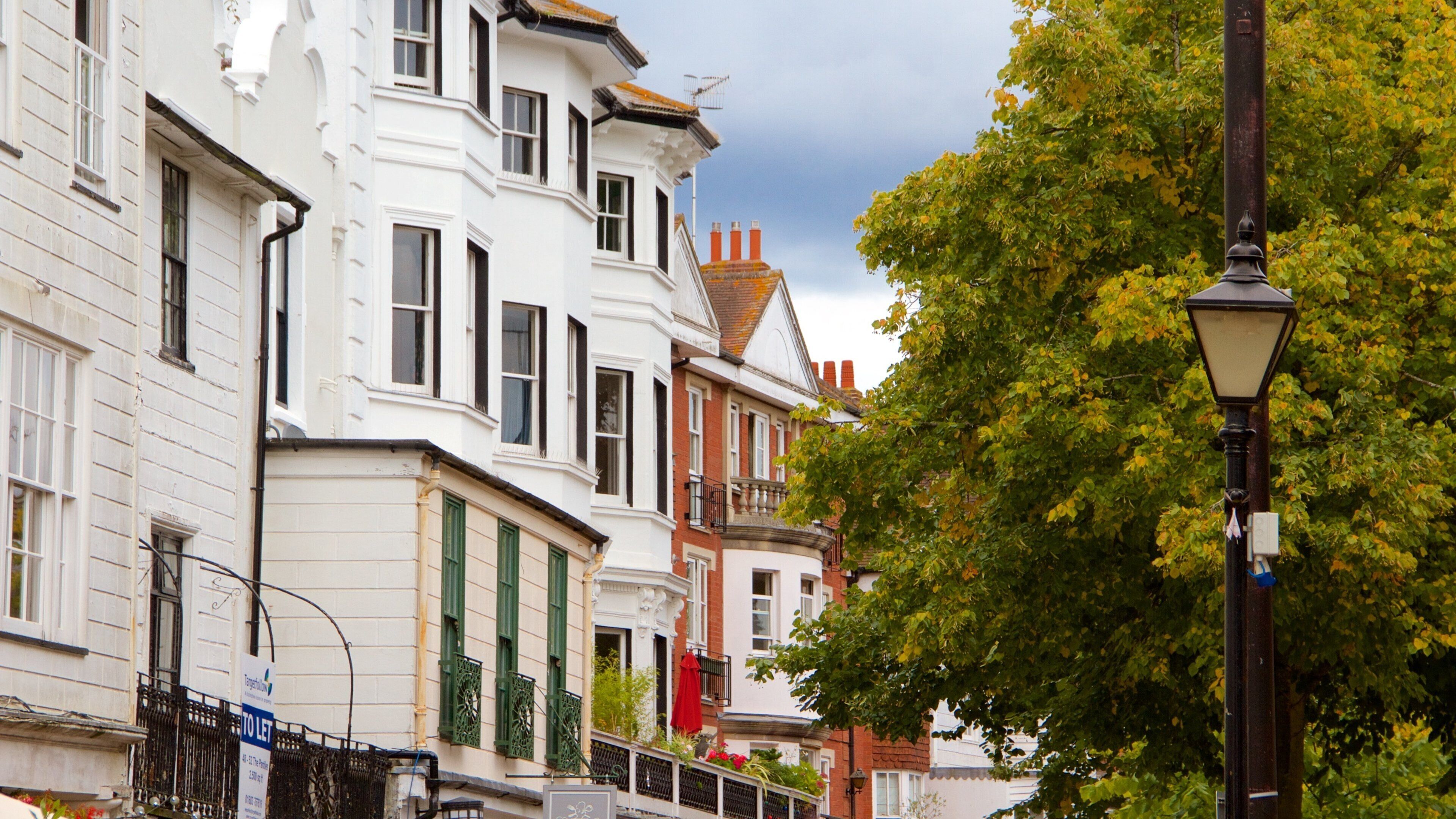 A row of Victorian-style houses with green shutters and a street lamp.