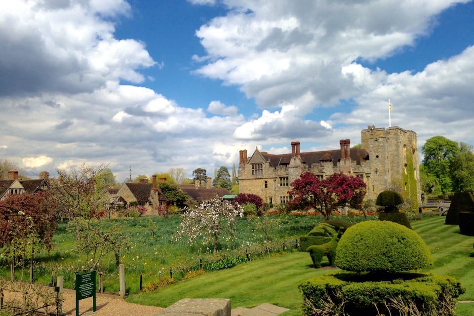 A historic castle surrounded by well-maintained gardens and a clear blue sky.