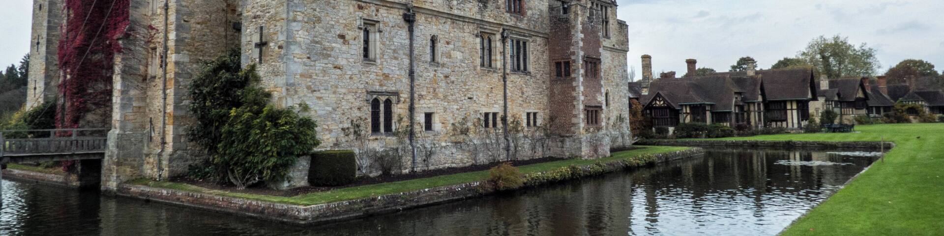 A historic stone castle with a moat, surrounded by traditional houses.