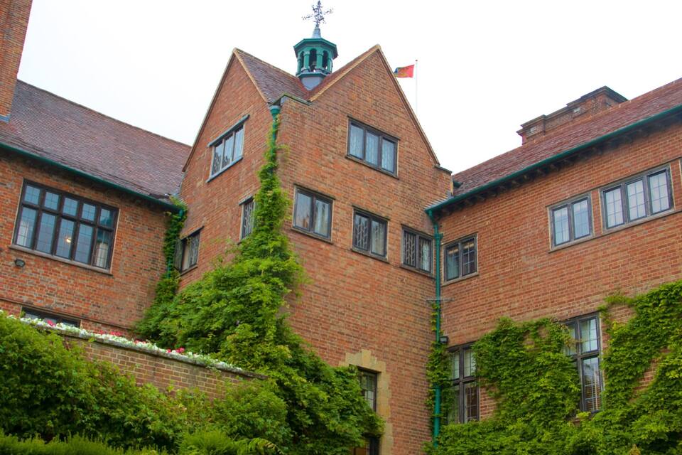 A red brick building with a tower, ivy, and a flag.