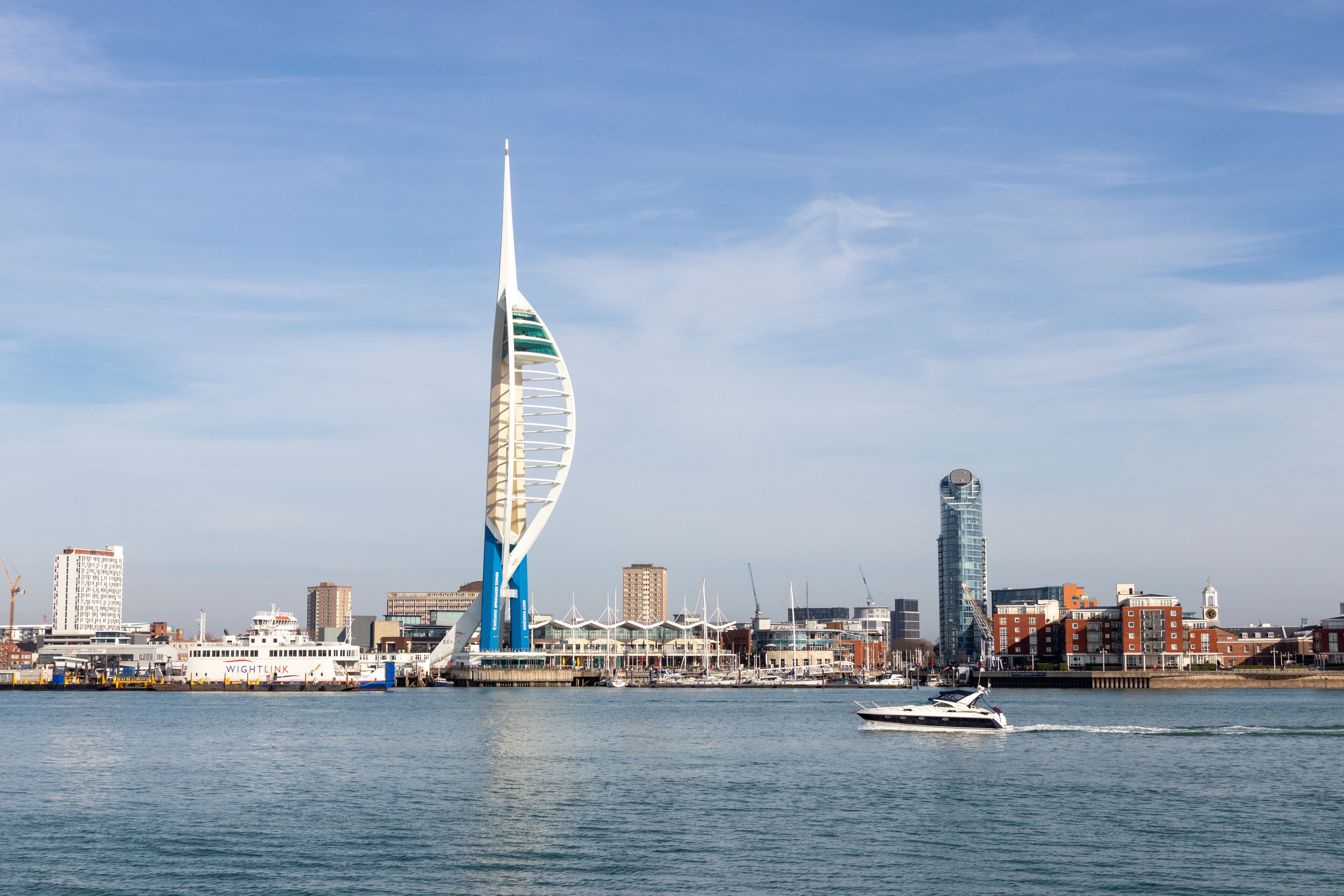 The spinnaker tower with a speedboat in the foreground and gunwharf quays with the spinnaker tower in the background