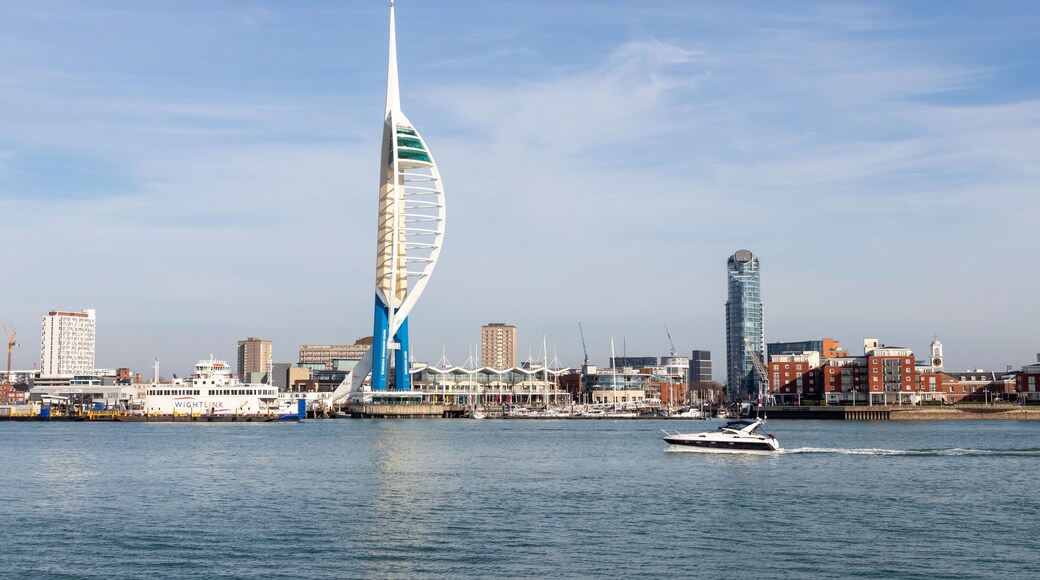 A modern sail-shaped building, a marina with boats, and a city skyline with various buildings.