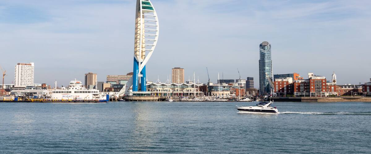 A modern sail-shaped building, a marina with boats, and a city skyline with various buildings.