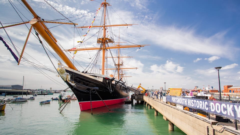 A large sailing ship docked at a harbor with a dock labeled "Portsmouth Historic Dockyard".