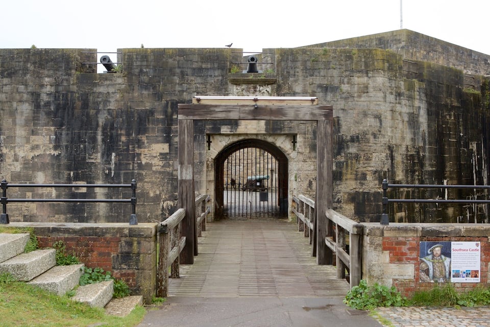 A historic fort entrance with cannons, a wooden archway, and a sign about Southsea Castle.