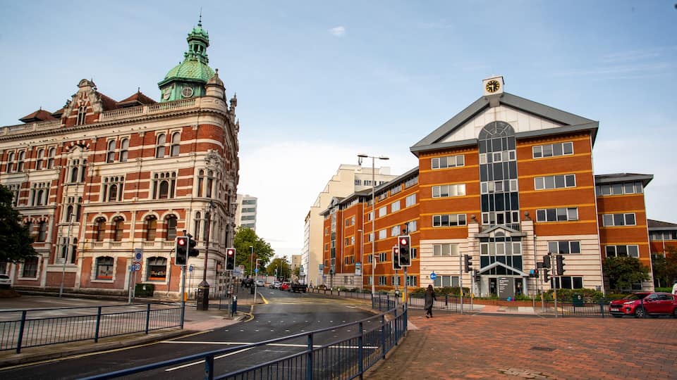 A street with historic buildings, a pedestrian crossing, and a red car.