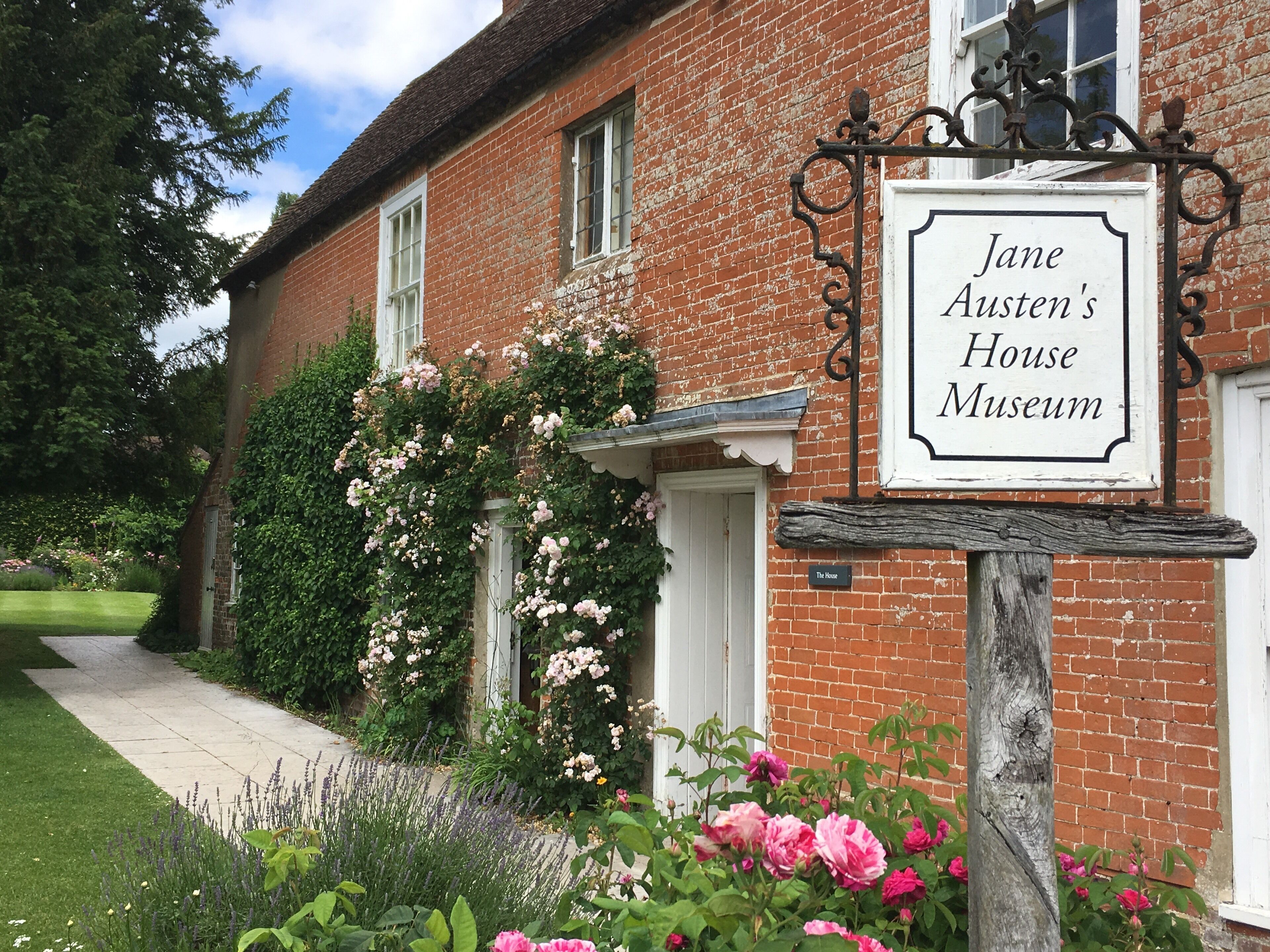 Jane Austen's House Museum with a brick facade, white door, and a signboard.
