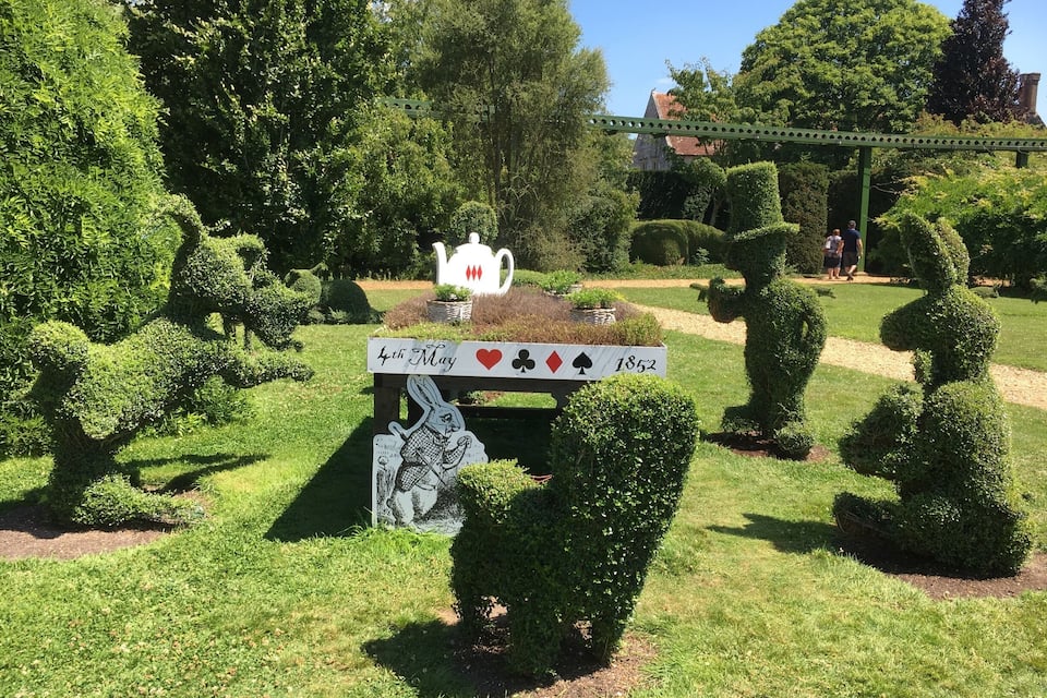 Un jardín con un cartel que dice "4 de mayo" y una escultura de tetera.