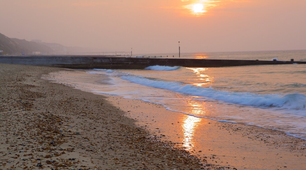 Playa de Bournemouth mostrando un atardecer y una playa de piedras