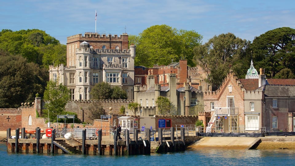 A historic waterfront with a castle-like building, a dock, and a small bridge.
