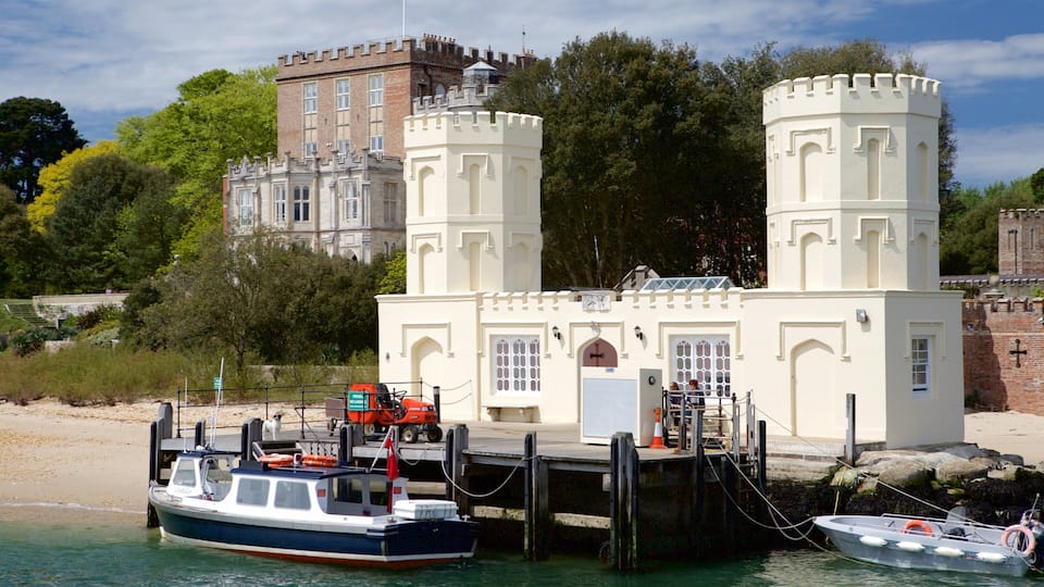 A castle with two towers, a boat docked at a pier, and a beach in the background.