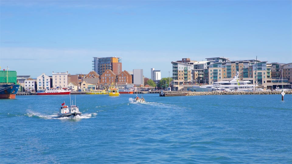 A harbor with boats, a red and white ship, and modern buildings in the background.