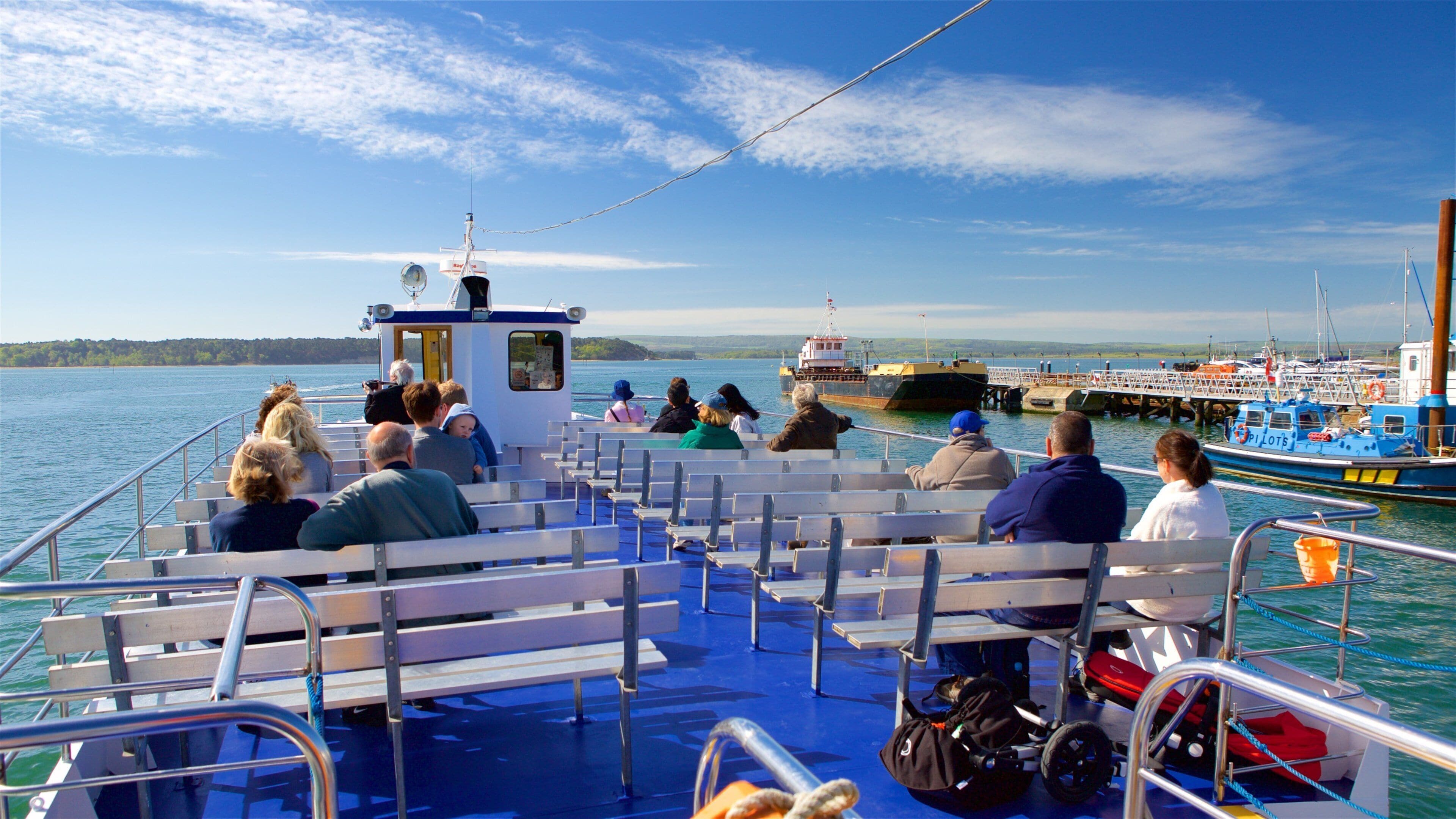 A ferry with passengers looking at the dock.