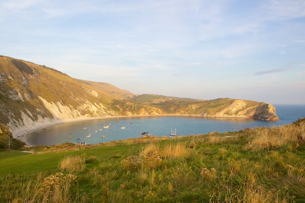 Un paysage côtier avec des falaises, une plage et des bateaux sur l’eau.