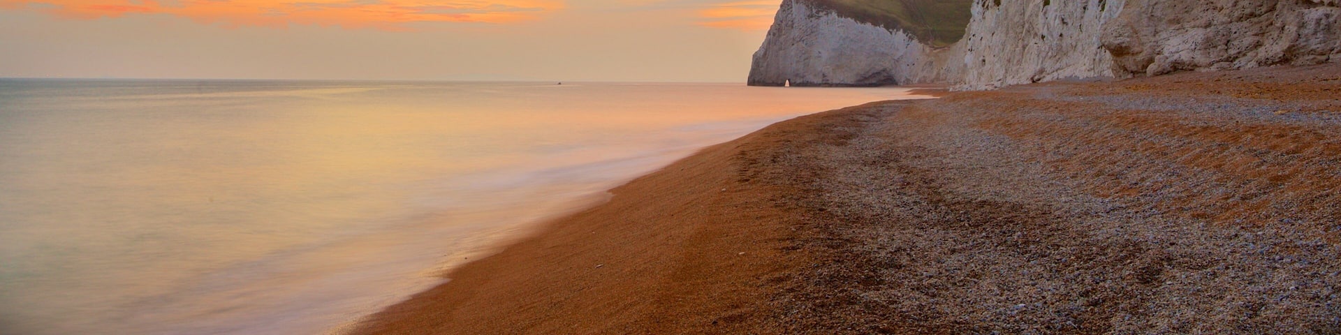 Durdle Door showing a pebble beach, a sunset and rocky coastline