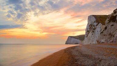 Durdle Door showing a pebble beach, a sunset and rocky coastline