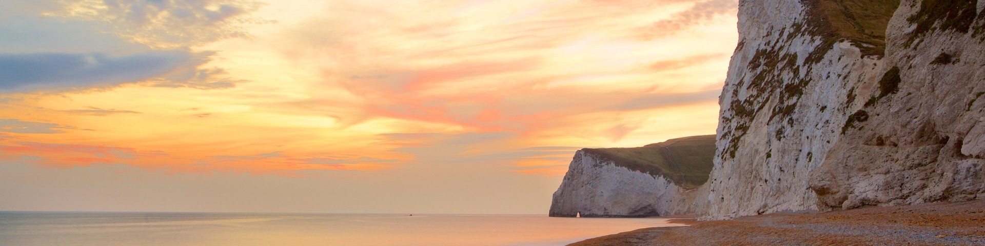 Durdle Door showing a pebble beach, a sunset and rocky coastline