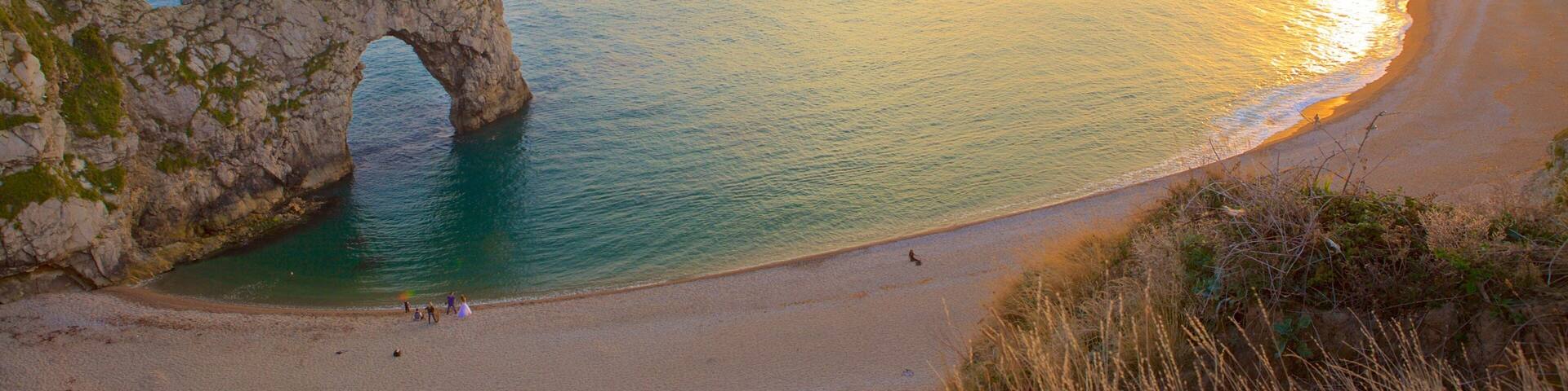 Durdle Door mettant en vedette baie ou port, coucher de soleil et côte escarpée