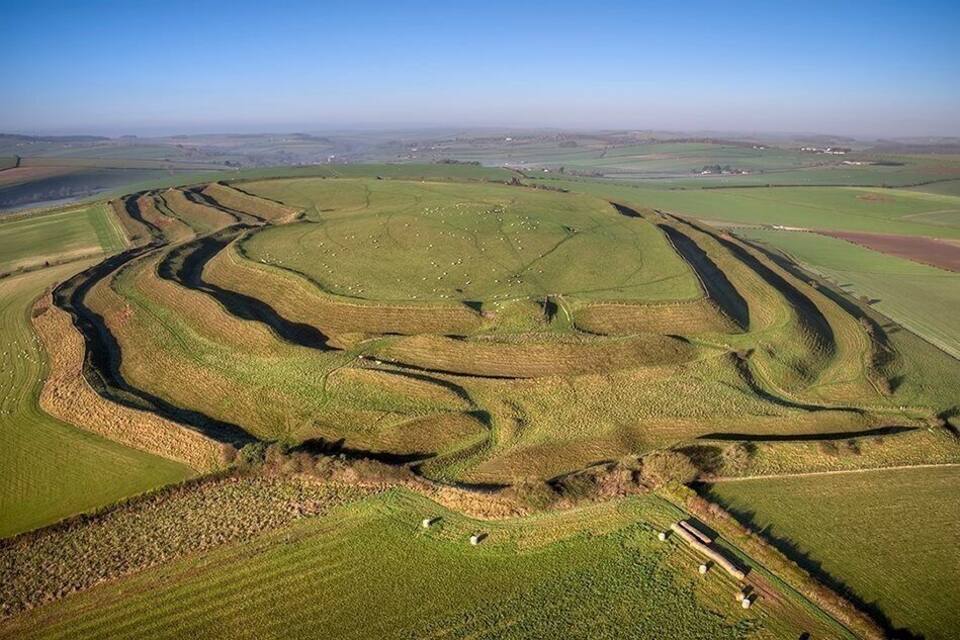 Een uitgestrekt landschap met terrassen en een kronkelende waterloop.