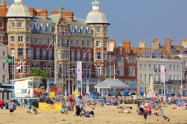 Weymouth Beach das einen Sandstrand sowie groĂe Menschengruppe