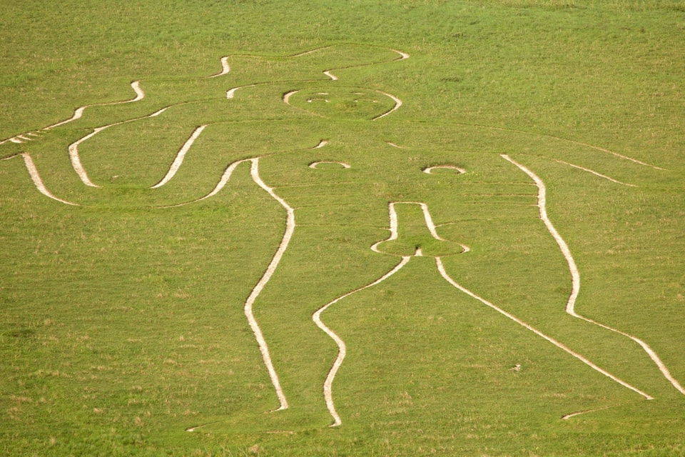 A large, intricate grass art installation featuring abstract figures.