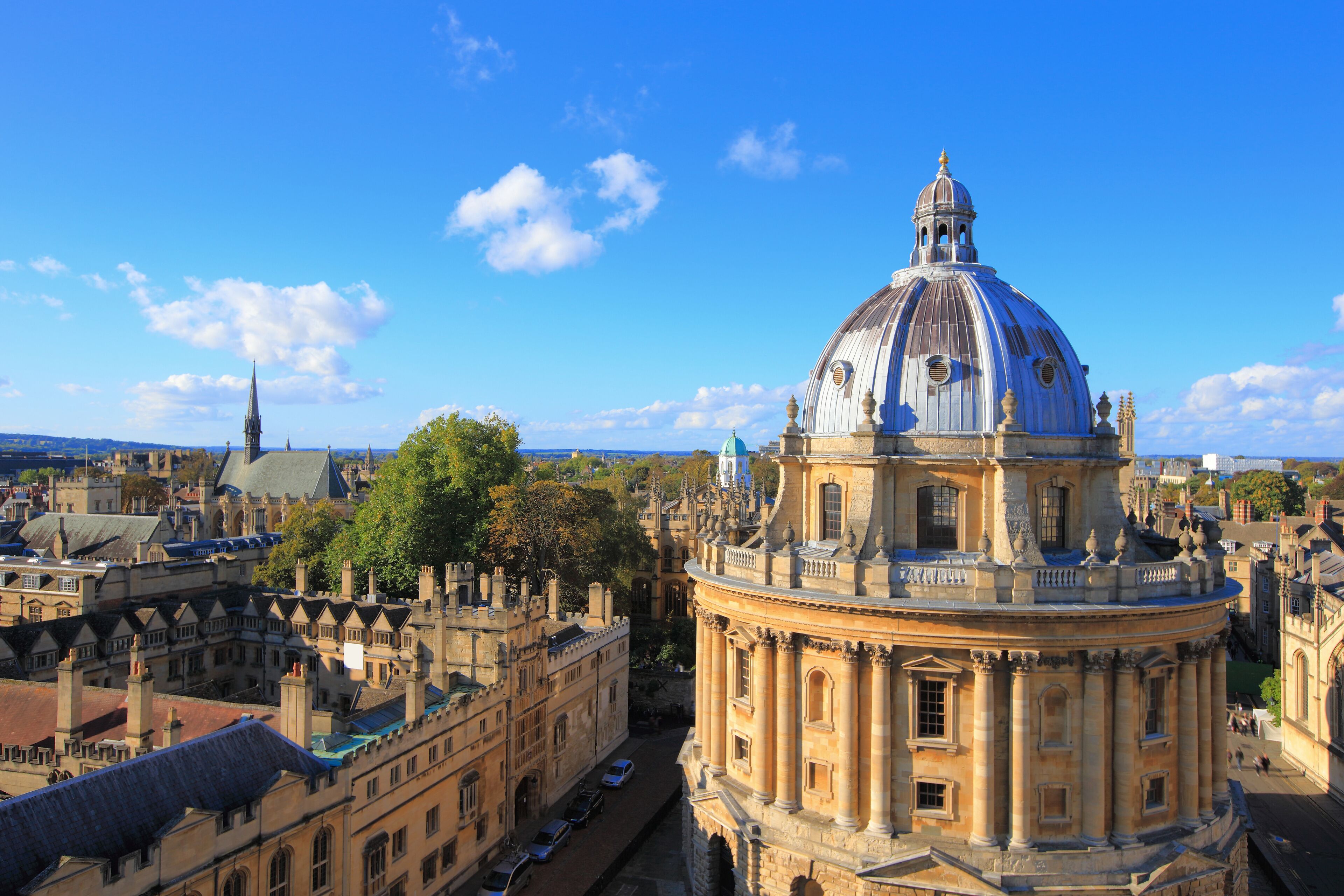 A historic building with a prominent dome and classical architecture, surrounded by other historic buildings and a clear blue sky.