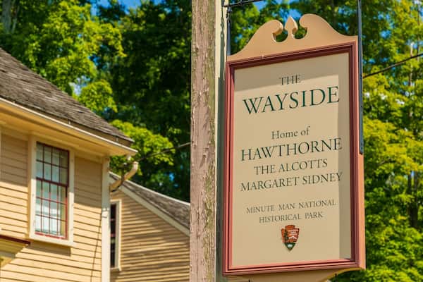 Une plaque signalétique portant l’inscription : « The Wayside, demeure de Hawthorne, des Alcott, de Margaret Sidney, parc historique national de Minute Man. »