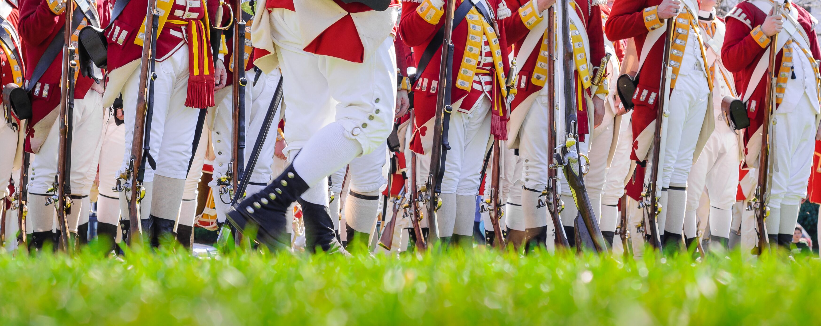 Legs of British soldiers of American revolutionary war on green battlefield in Lexington, MA