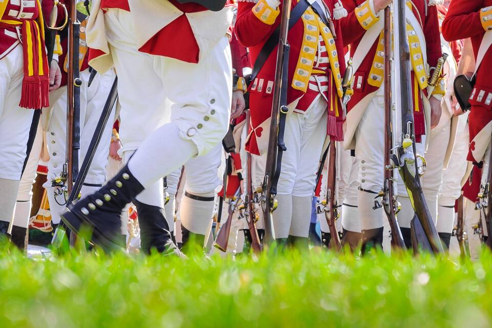 A group of soldiers in red and white uniforms standing in formation with rifles.
