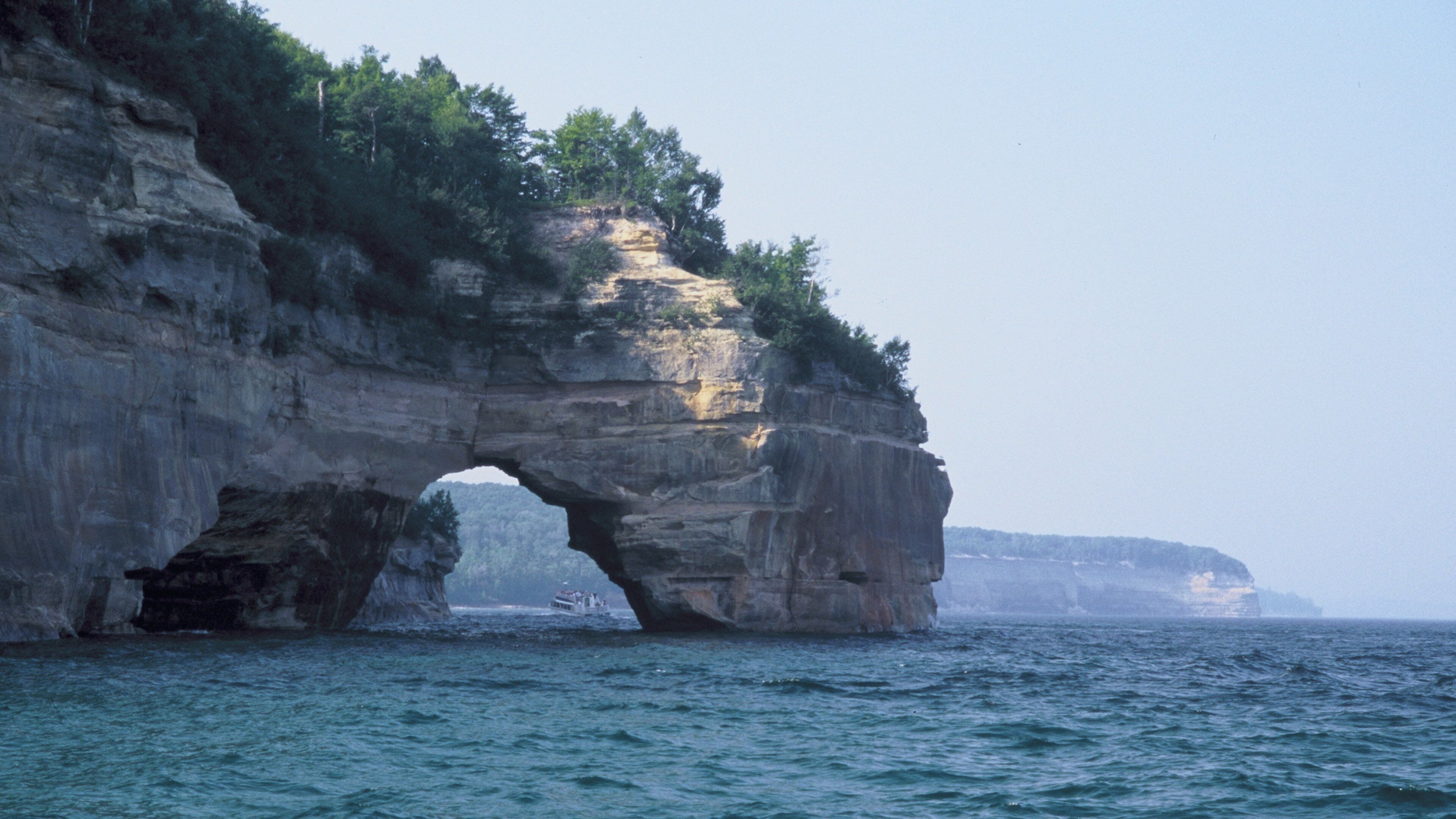 A large rock formation with a natural arch over the water.