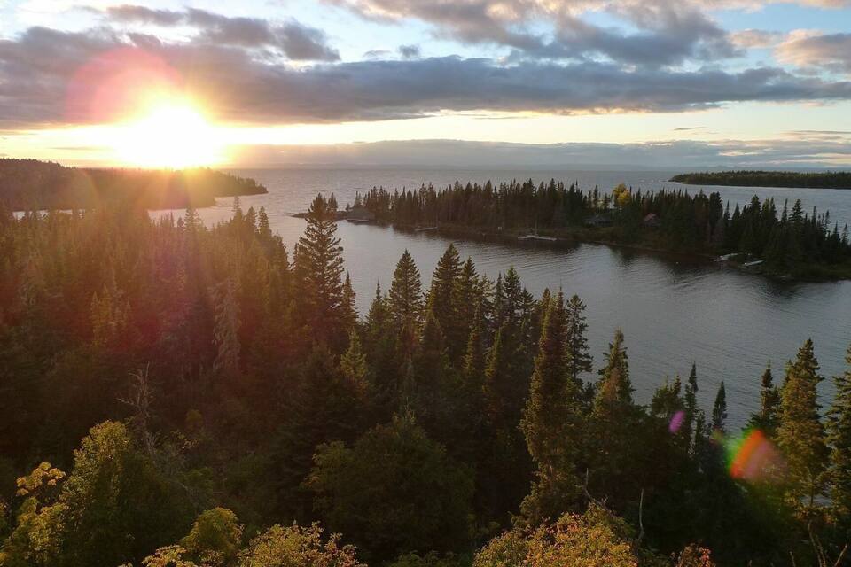 A sunset over a lake surrounded by dense forest.