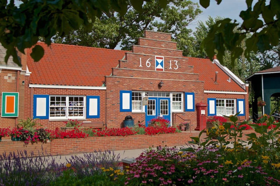 A brick building with a red roof and blue shutters, marked with the number 16 and 13.