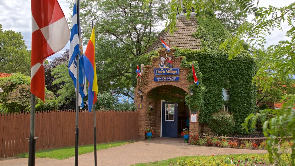 A brick building with a blue door and a sign reading "Dutch Village." Flags are flying in front of the building.