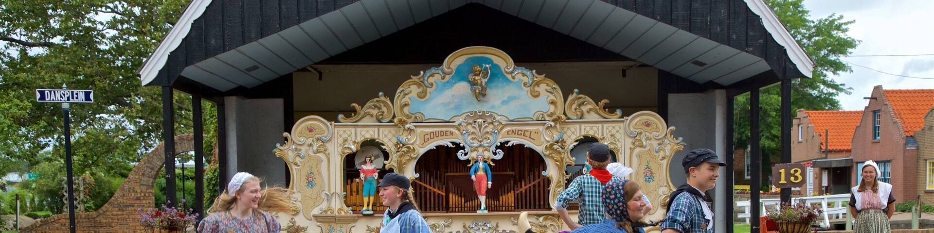 A traditional Dutch dance performance in front of a church with ornate decorations and a sign reading "DANSPEIN".