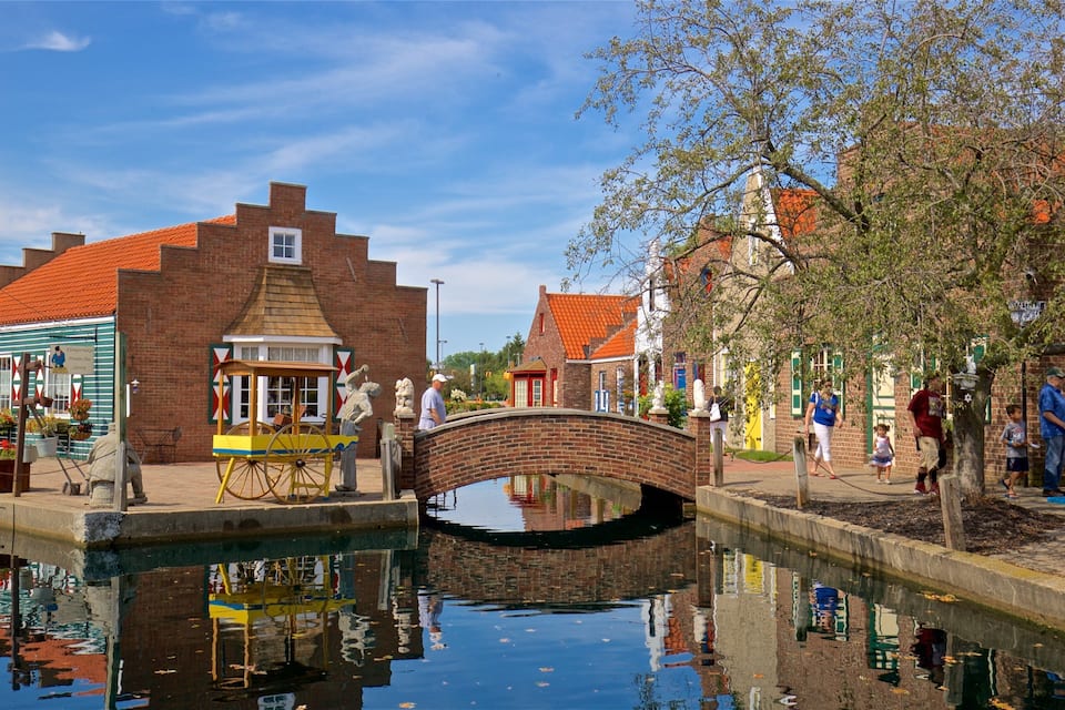 A canal with a bridge, brick buildings, and a small wooden cart.