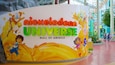A Nickelodeon Universe sign with cartoon characters and a splash of yellow paint.