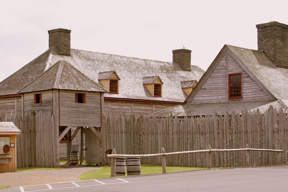 A wooden building with a wooden fence, a wooden sign, and a wooden bench.