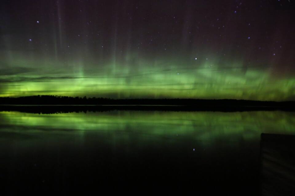 Auroras boreales sobre un lago tranquilo en la noche.