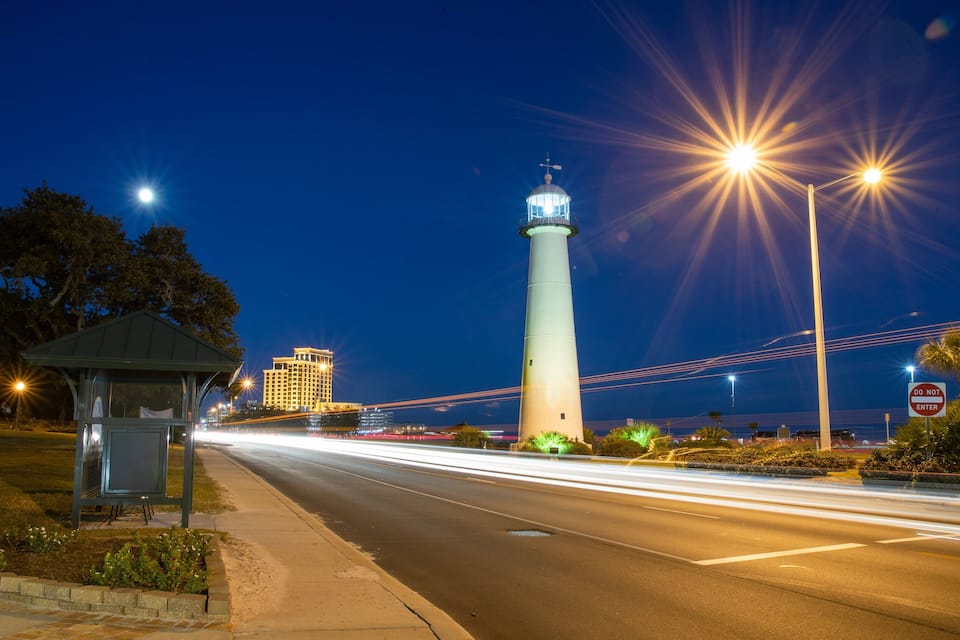 Un faro, una carretera y un puente de noche.