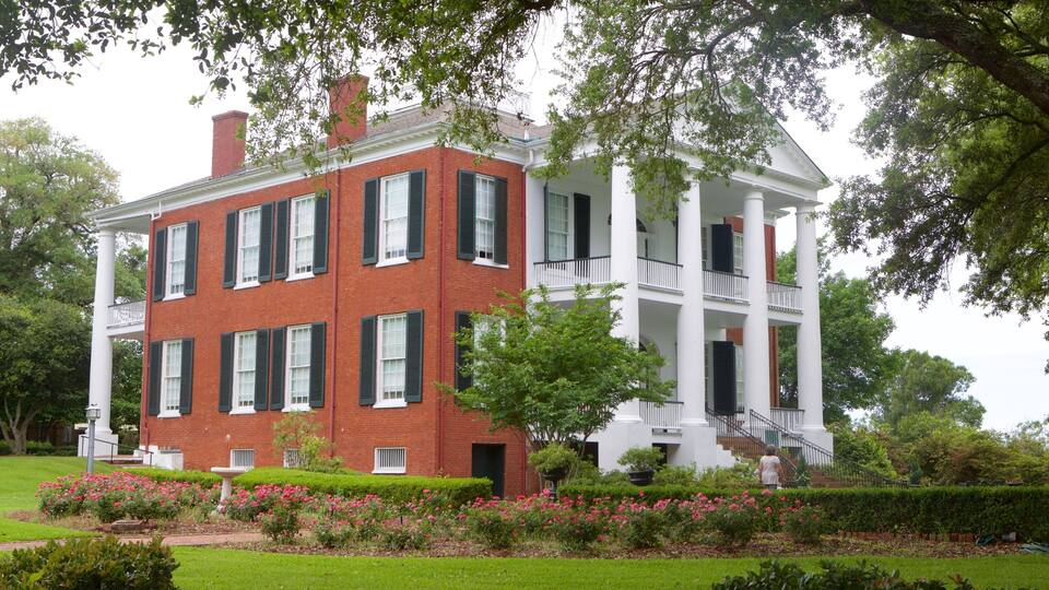 A large brick building with white columns and a balcony.