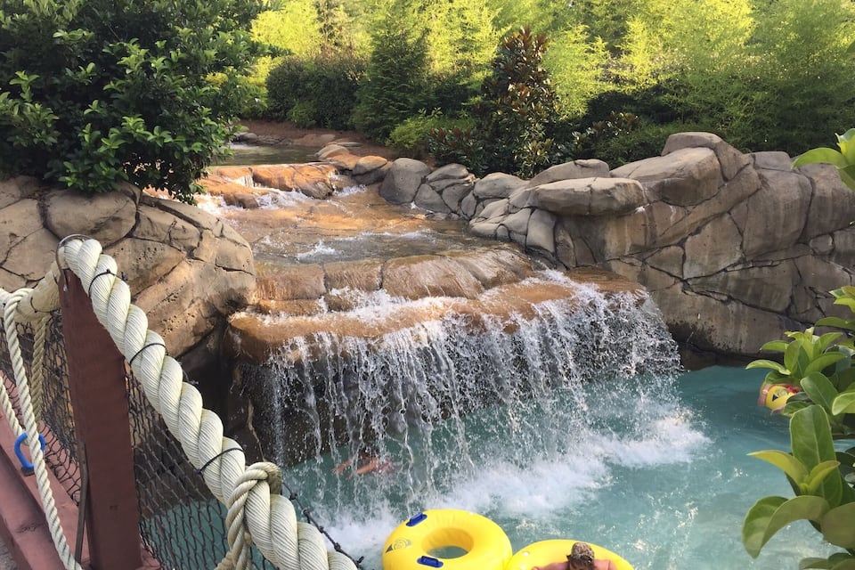 A water park with a cascading waterfall, a rope net, and inflatable rings.