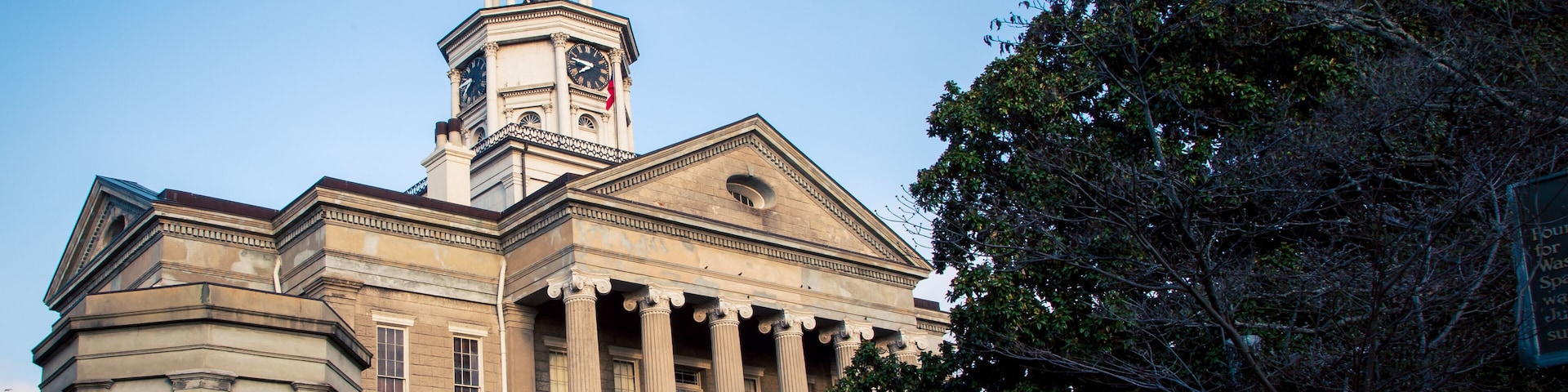 A neoclassical building with a clock tower, columns, and a dome.