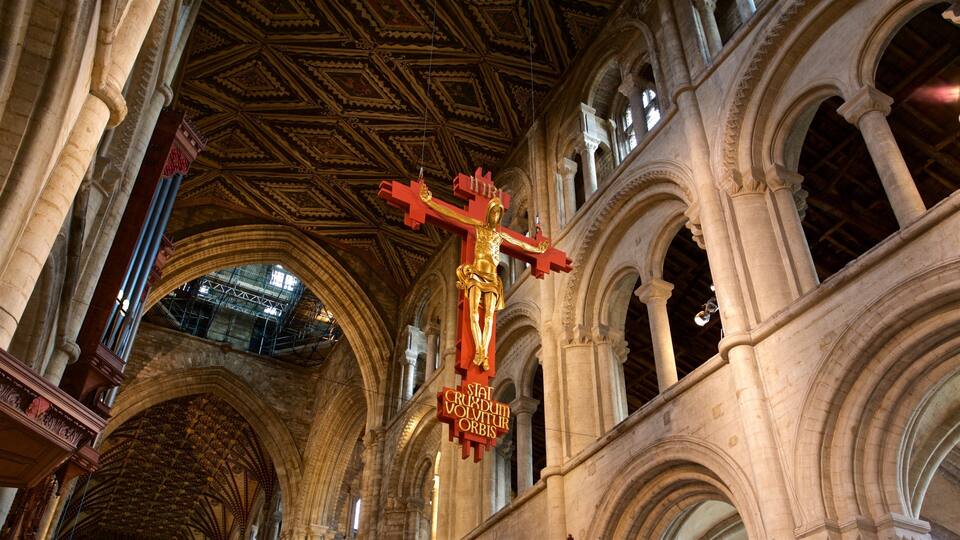 A cathedral interior with a golden crucifix, arched columns, and a patterned ceiling.